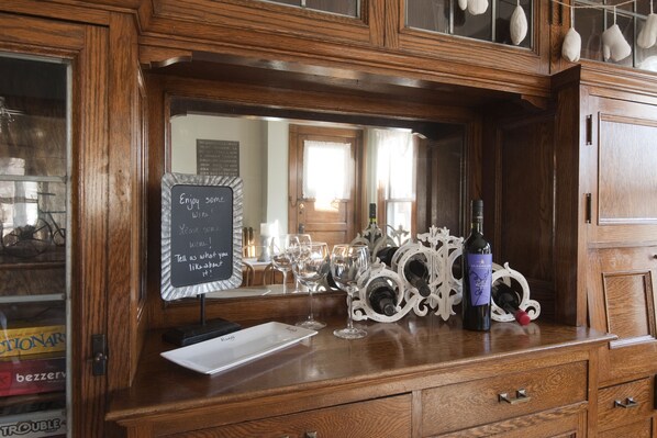 A wooden counter with wine glasses, a bottle of wine, and a chalkboard sign.