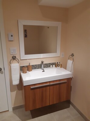A bathroom with a white sink, wooden cabinets, a mirror, and a towel rack. - Sentinel Mountain view Flat, outdoor activities & parks right at your doorstep (Castlegar)