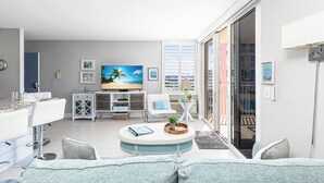 Ein modernes Wohnzimmer mit Fernseher, Sitzecke und großem Fenster.