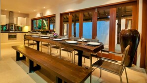 Un comedor moderno con una larga mesa de madera dispuesta para una comida, rodeada de sillas.