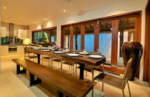 Un espace de restauration moderne avec une longue table en bois dressée pour un repas, entourée de chaises.