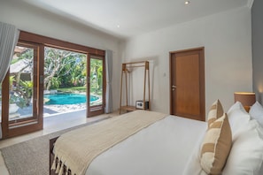 Une chambre avec un grand lit, une armoire en bois et une vue sur une piscine.