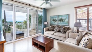 A living room with a sofa, coffee table, and artwork on the wall. - 1 BD,1.5 Bathroom, Beautiful Condo (Providenciales)