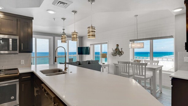 A modern kitchen with a large island, stainless steel appliances, and pendant lighting.