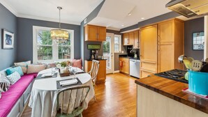 A modern kitchen with wooden cabinets, a dining area with a round table and chairs, and a built-in bench with cushions. - Del Ray Designer Home walk to Shops, Cafes, Fun (Alexandria)