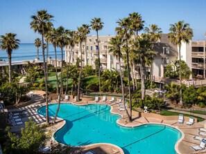 Un resort con una gran piscina, palmeras y vista al océano.