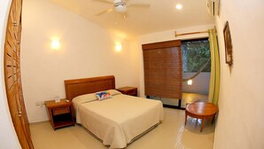 A bedroom with a bed, bedside tables, a ceiling fan, an air conditioning unit, a window with a view, and a small table. - 2 Bedroom Apartment In Quiet Secure Residential Complex Surrounded By Nature (Akumal)