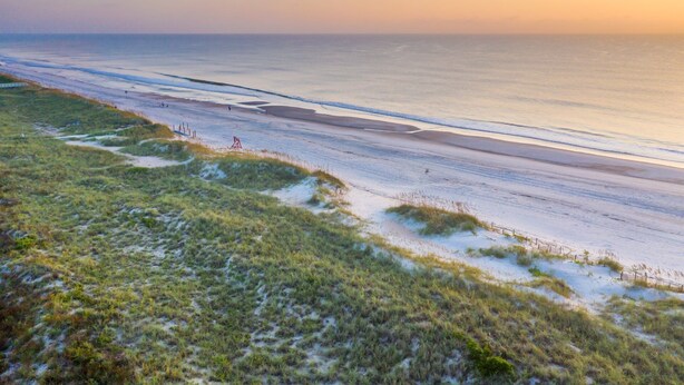 Une plage avec des dunes de sable et une clôture le long du rivage.