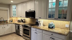 A modern kitchen with white cabinets, stainless steel appliances, and a granite countertop. - Relax by the sea! 3-Bedroom Delray Beach Home near Atlantic Ave (Delray Beach)