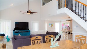 A spacious living area with a wooden dining table, a sofa, and a television. - Relax by the sea! 3-Bedroom Delray Beach Home near Atlantic Ave (Delray Beach)