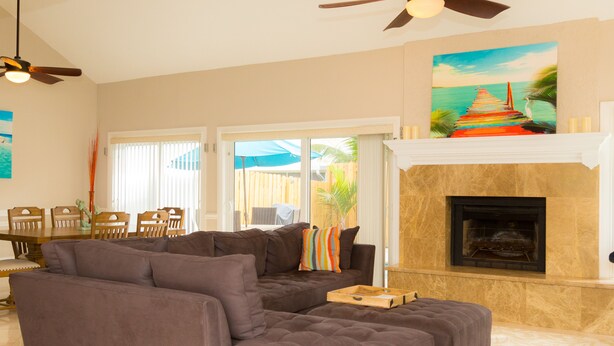 A living room with a sectional sofa, a fireplace, and a painting of a beach scene. - Relax by the sea! 3-Bedroom Delray Beach Home near Atlantic Ave (Delray Beach)