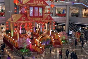 A multi-level shopping mall with a festive display featuring traditional architecture and red lanterns. - King Sa Hotel (Shishi)