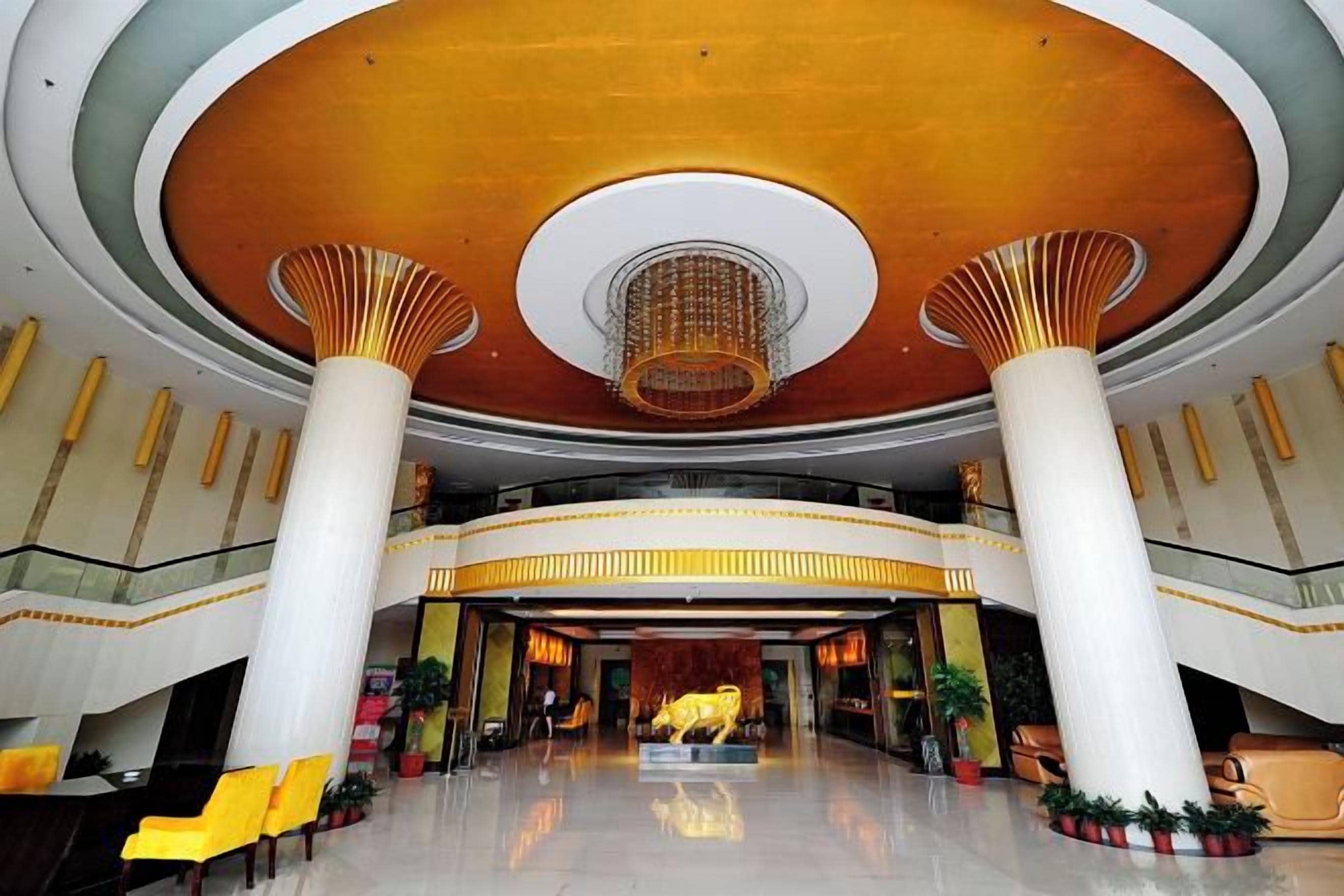 A spacious lobby with a high ceiling, large columns, and a central chandelier.
