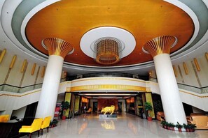 A spacious lobby with a high ceiling, large columns, and a central chandelier. - King Sa Hotel (Shishi)
