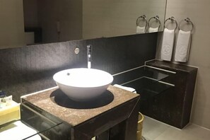 A modern bathroom with a large white vessel sink, dark marble countertops, and a large mirror. - King Sa Hotel (Shishi)