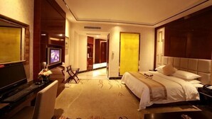 Habitación de hotel con cama, escritorio, televisor y puerta que da a otra habitación.