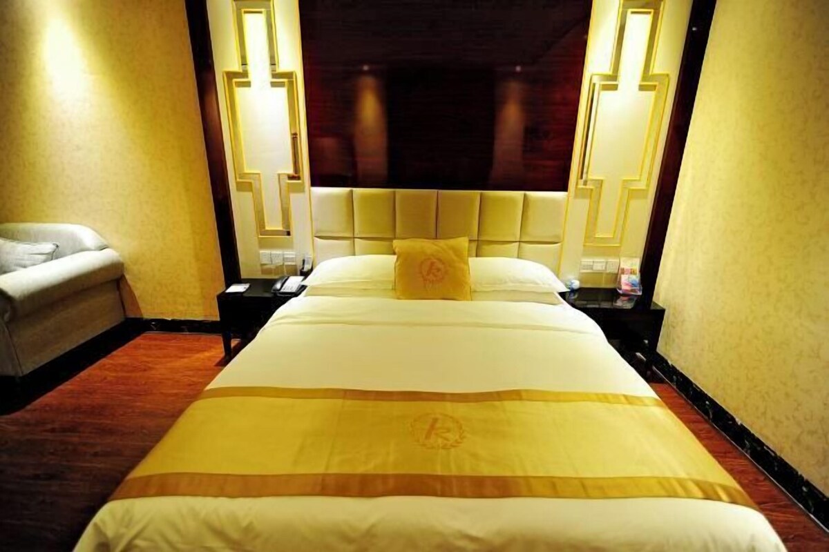 A hotel room with a large bed, a headboard, two bedside tables, and a nightstand.