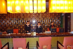 A reception area with a marble counter, red chairs, and a wall of framed pictures.