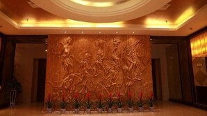 Un vestíbulo con una gran pared escultórica, plantas en macetas y un diseño de techo circular.