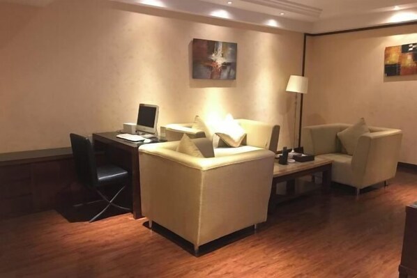A hotel room with a desk, two armchairs, a lamp, and artwork on the walls. - King Sa Hotel (Shishi)