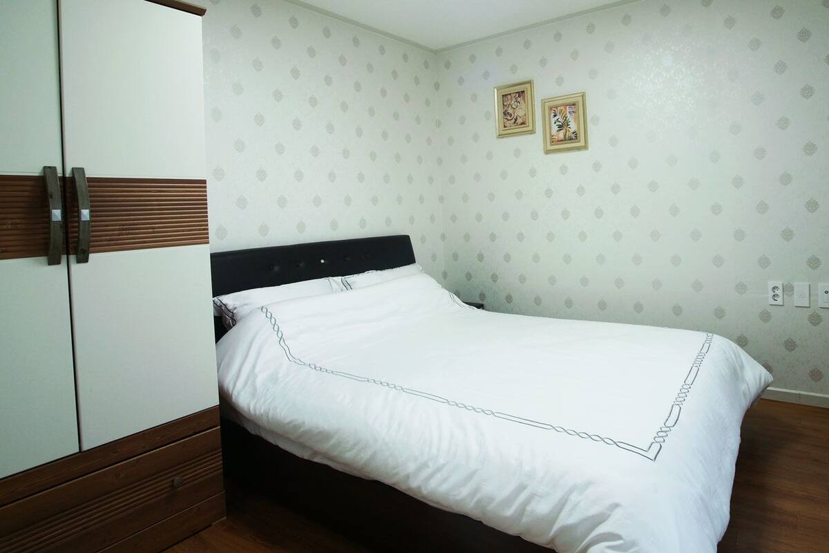 A bedroom with a bed, a wardrobe, and a door.
