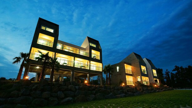 A modern two-story house with a balcony, large windows, and a stone foundation. - Jeju J Pension (Seogwipo)