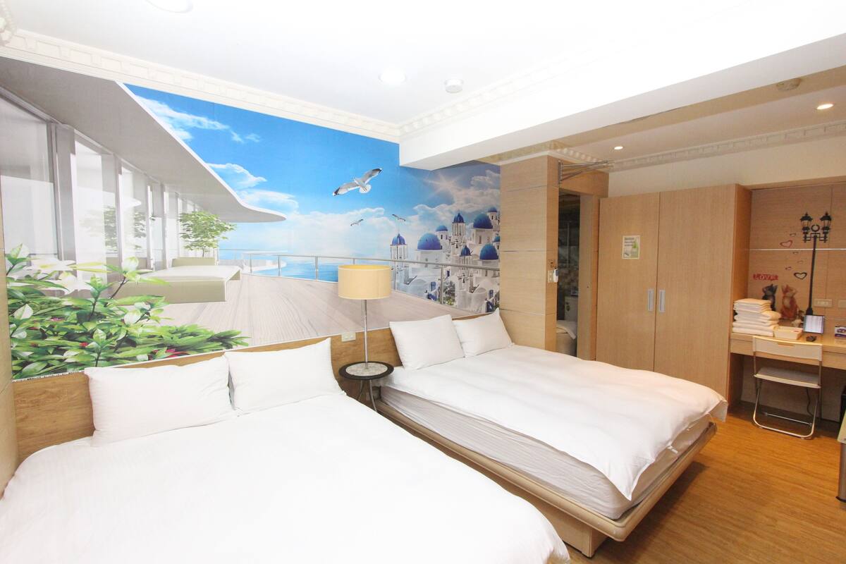 A hotel room with two beds, a desk, a chair, a lamp, and a view of a blue sky with clouds and seagulls.