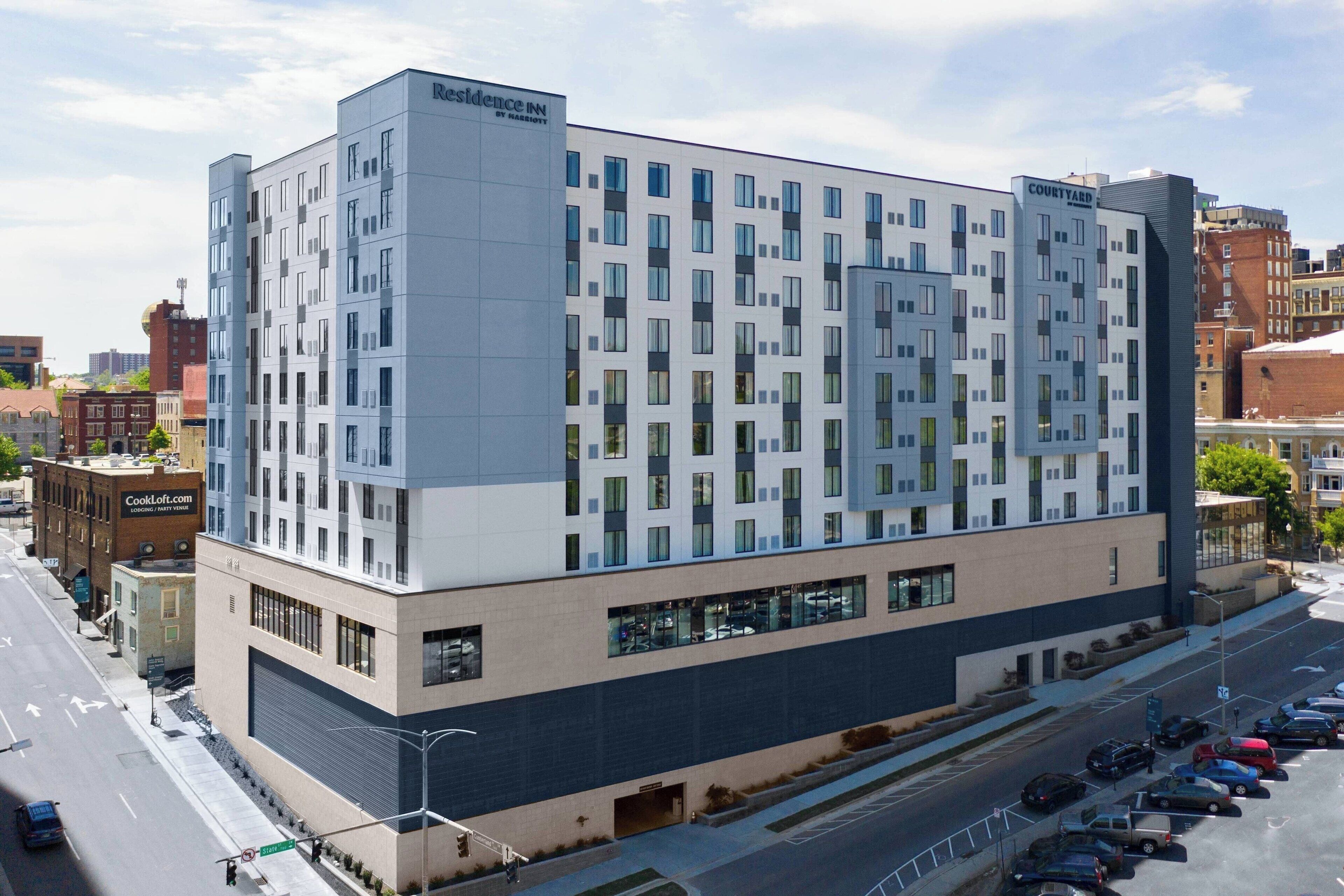 Ein modernes Hotel mit einer rasterförmigen Fassade, großen Fenstern und einem Parkplatz davor.