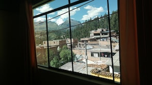 A window view of a town with buildings and mountains in the background.