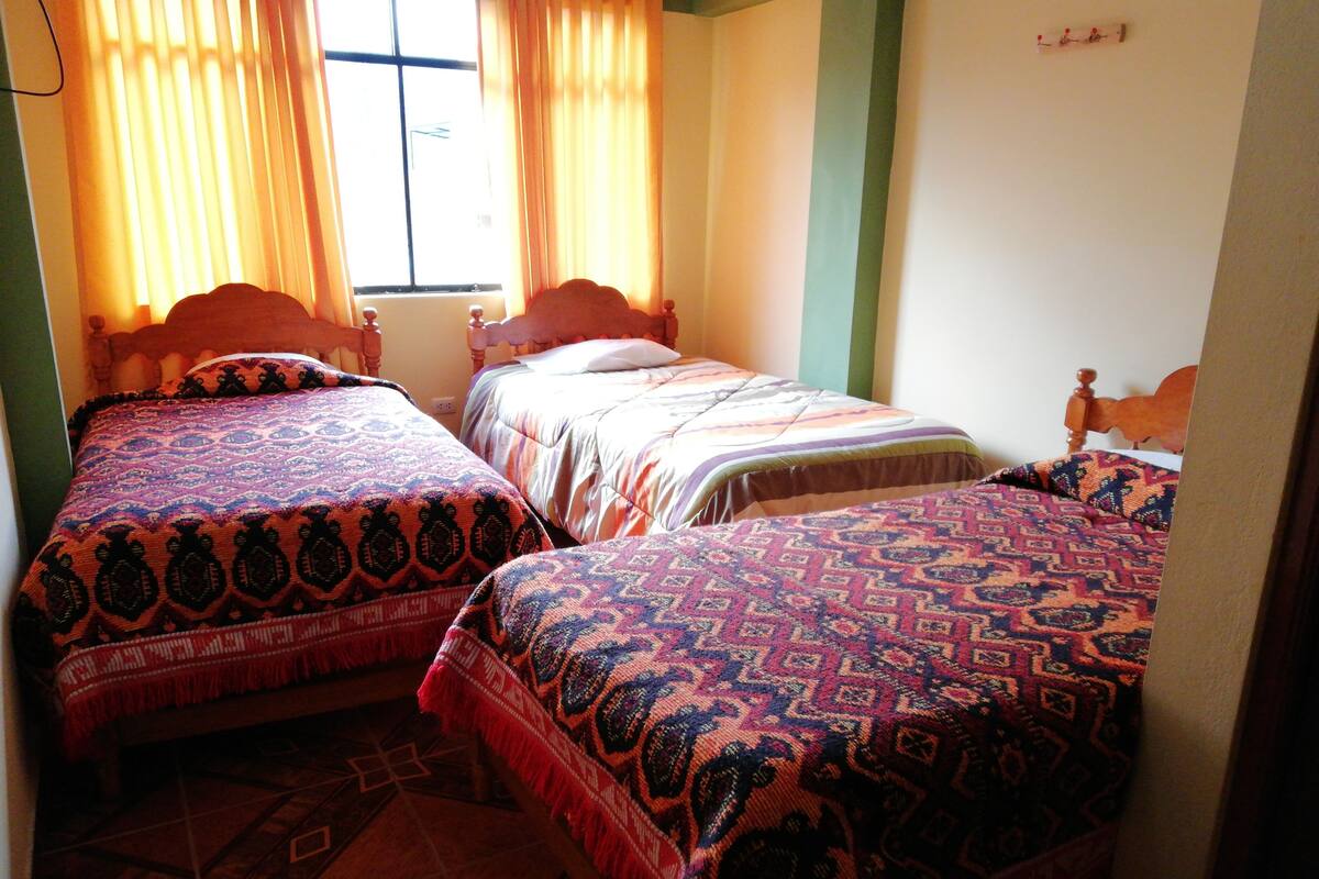 Una habitación con tres camas, cada una con ropa de cama estampada.