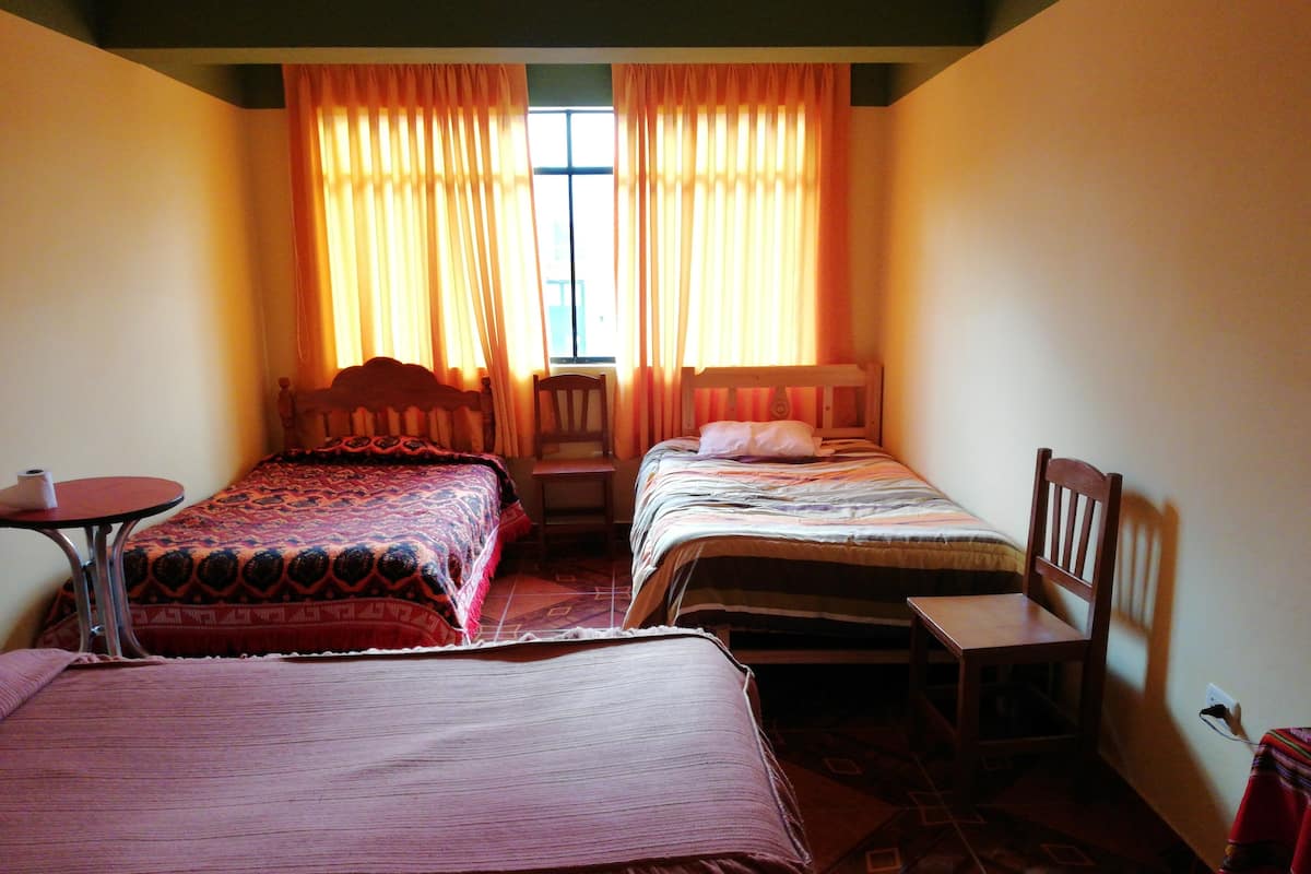 Una habitación con dos camas, una mesita y una silla.