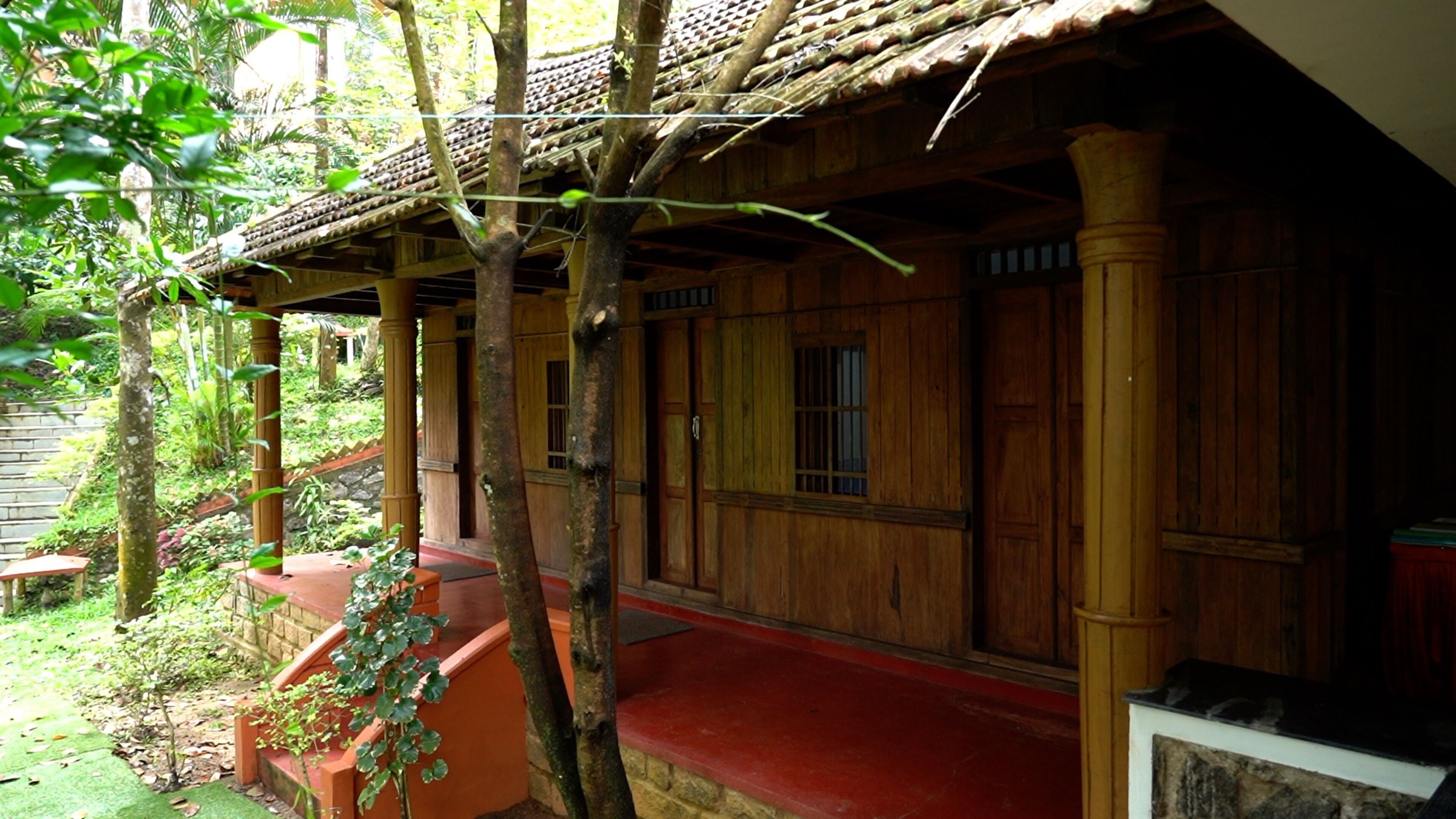 Una casa tradicional de madera con un porche rojo, puertas de madera y techo de tejas.