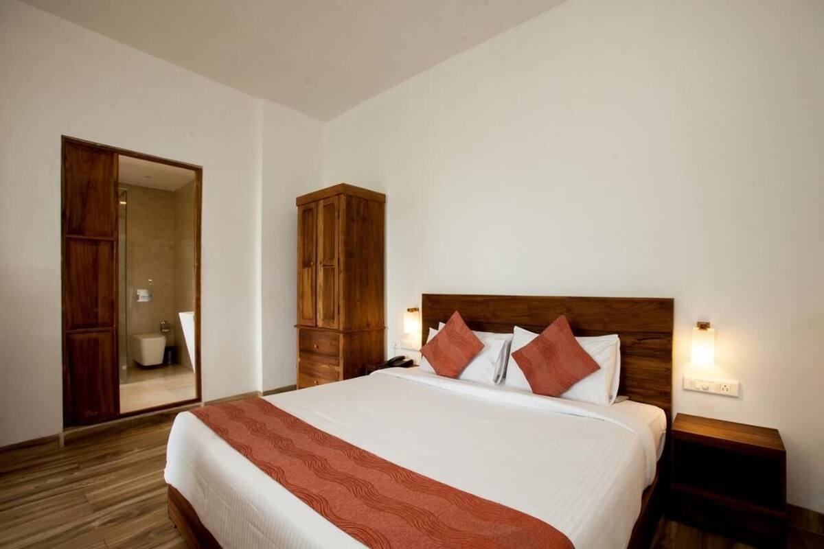 A hotel room with a large bed, wooden headboard, and a wardrobe.