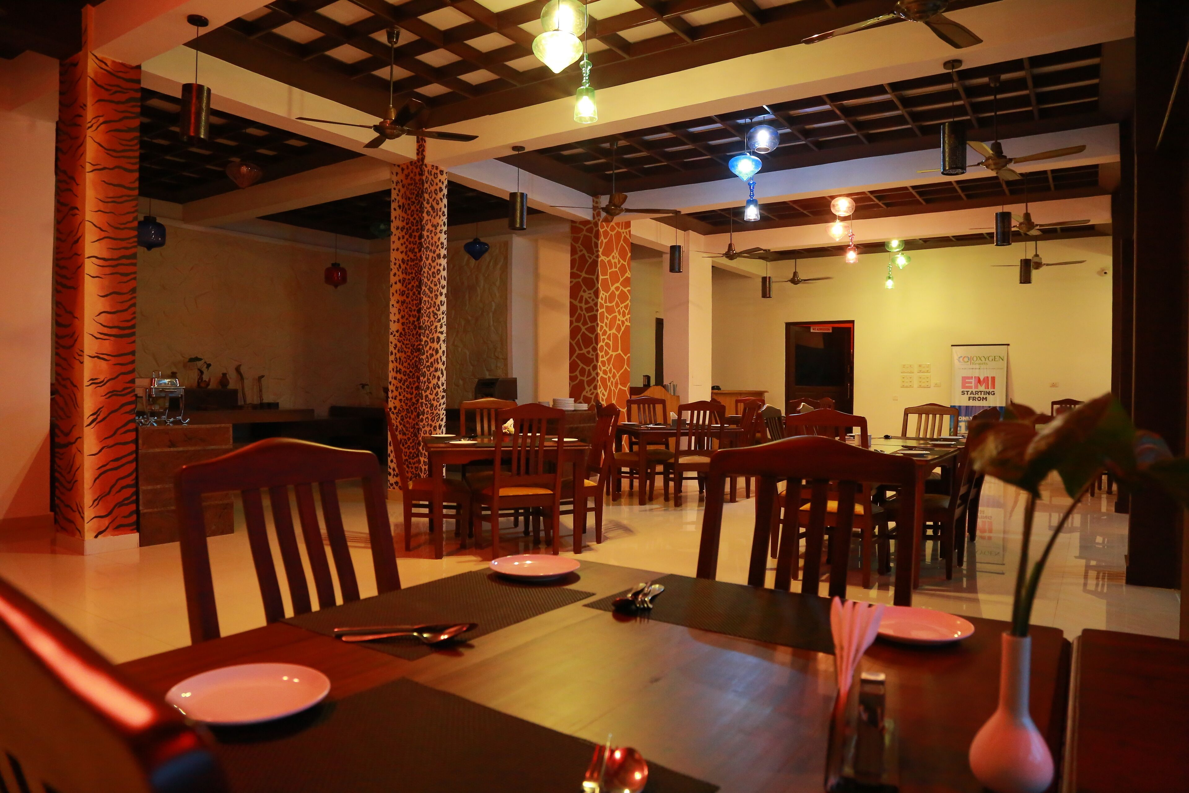 A restaurant with wooden furniture, hanging lights, and a ceiling fan.