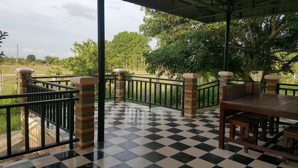 A checkered floor, outdoor seating, and a view of a green landscape. - Pings Farmstay (Somboon)