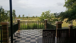 A checkered outdoor area with a metal railing, leading to a grassy field. - Pings Farmstay (Somboon)