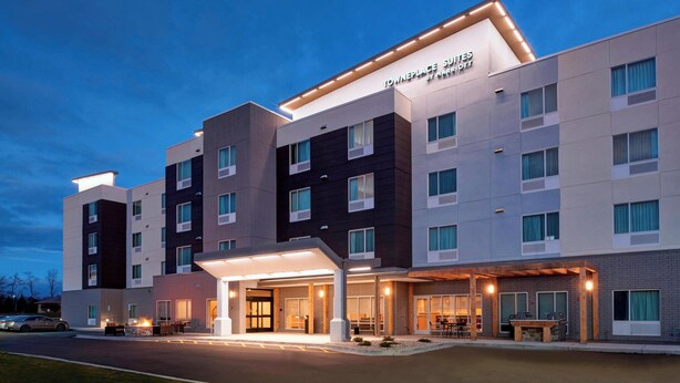 A modern hotel with a flat roof, multiple floors, and a well-lit entrance. - TownePlace Suites by Marriott Grand Rapids Airport (Grand Rapids)