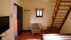 A bedroom with a bed, a chair, a TV, a wooden staircase, and a window. - Blue mountain inn (Jinning)