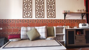 A room with a sofa, patterned cushions, a wall-mounted shelf with kitchen items, and decorative panels. - Blue mountain inn (Jinning)