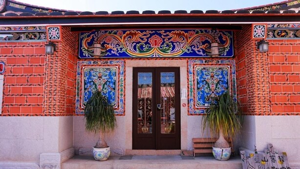 A building with a traditional facade, featuring a tiled entrance and two potted plants. - Blue mountain inn (Jinning)
