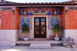 A building with a traditional facade, featuring a tiled entrance and two potted plants. - Blue mountain inn (Jinning)