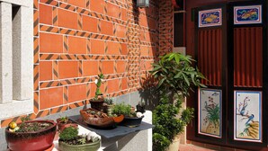 A tiled wall with a geometric pattern, a potted plant, and a door with traditional artwork. - Blue mountain inn (Jinning)