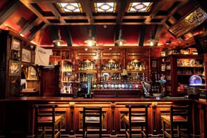 A bar with wooden furnishings, a variety of bottles, and a selection of beers. - Molloy's Apartments (Dublin)