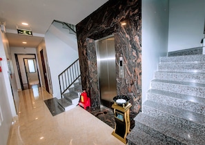 Enter a clean, contemporary lobby with a polished floor and elegant staircase.