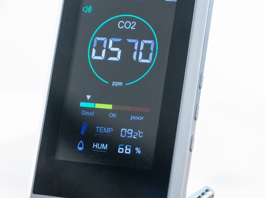 Ein digitales Gerät zur Überwachung der Luftqualität, das CO2-Werte, Temperatur und Luftfeuchtigkeit anzeigt.