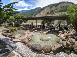 A hot spring area with a stone pathway, rocks, and a wooden structure. - Fangchen Hot Spring Resort (Kaohsiung)