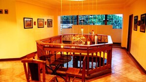 A dining area with a round table and chairs, a hanging light fixture, and framed artwork on the walls.