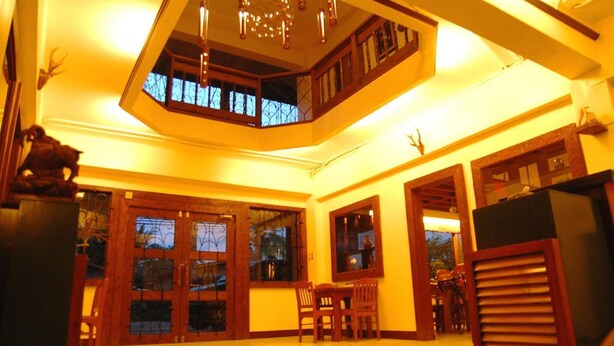 A spacious room with a high ceiling, a large window, and a staircase leading to an upper level.