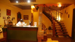 A reception desk with a person behind it, a staircase, and a wall with framed pictures.
