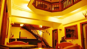 A multi-level interior with a staircase, wooden furniture, and a framed picture on the wall.
